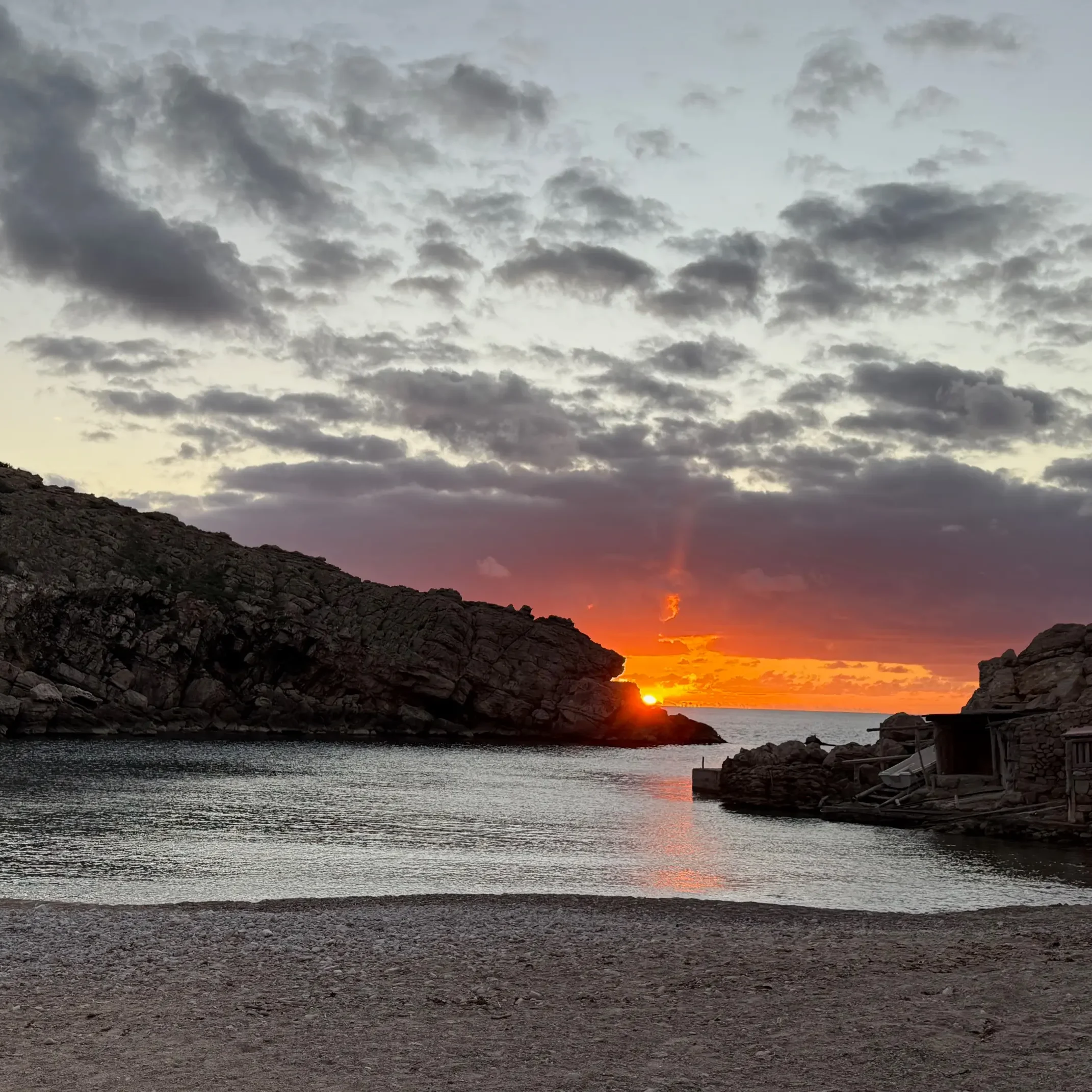 Puesta de sol en Cala Carbó con reflejos dorados sobre el mar