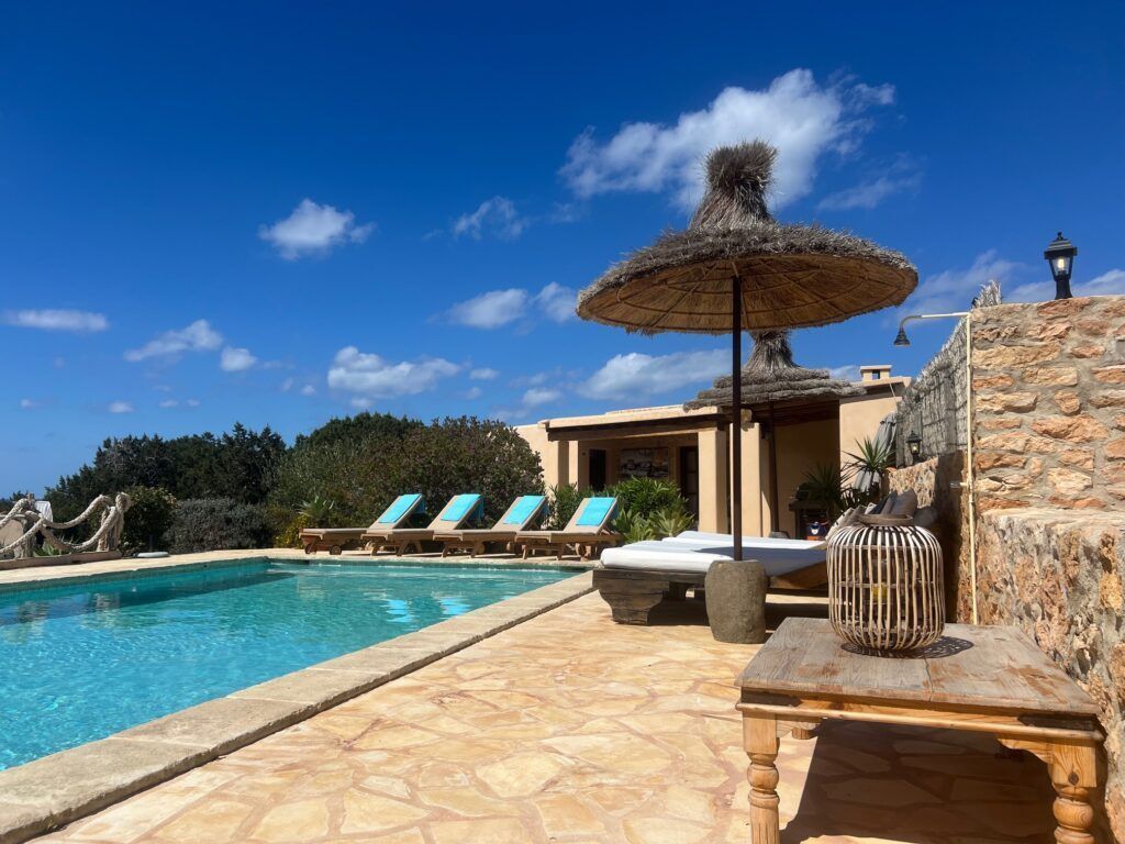 Piscina con tumbonas y sombrilla de paja en Sa Païssa den Botja Ibiza