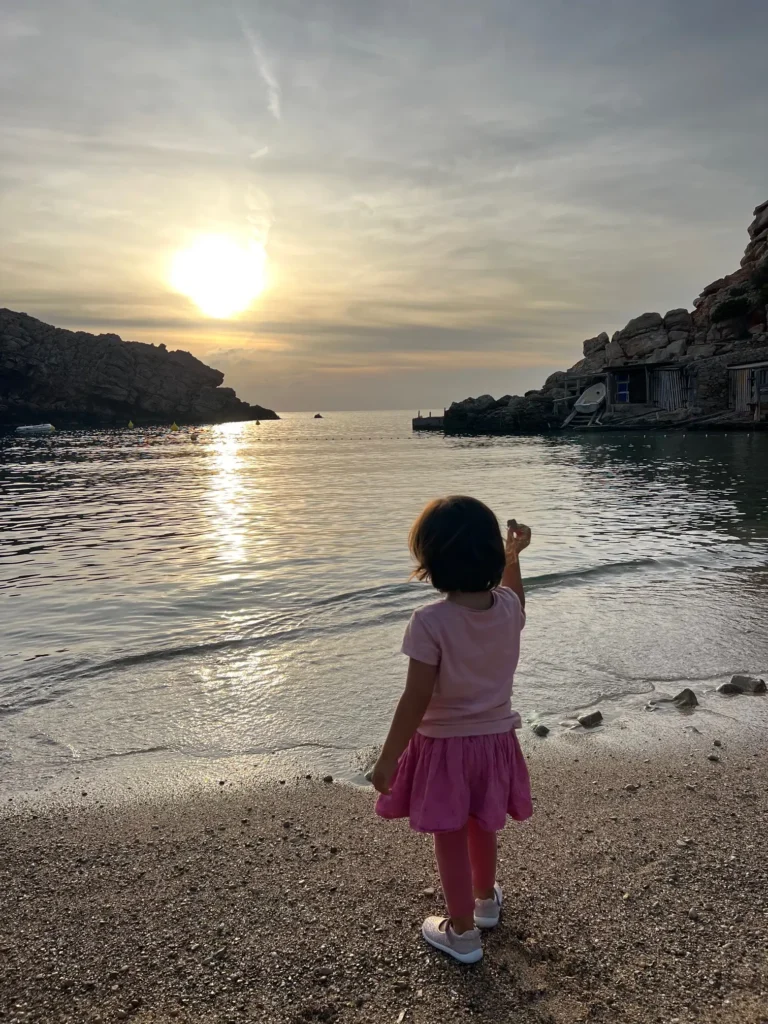 Atardecer en Cala Carbó con niña mirando el mar, Ibiza