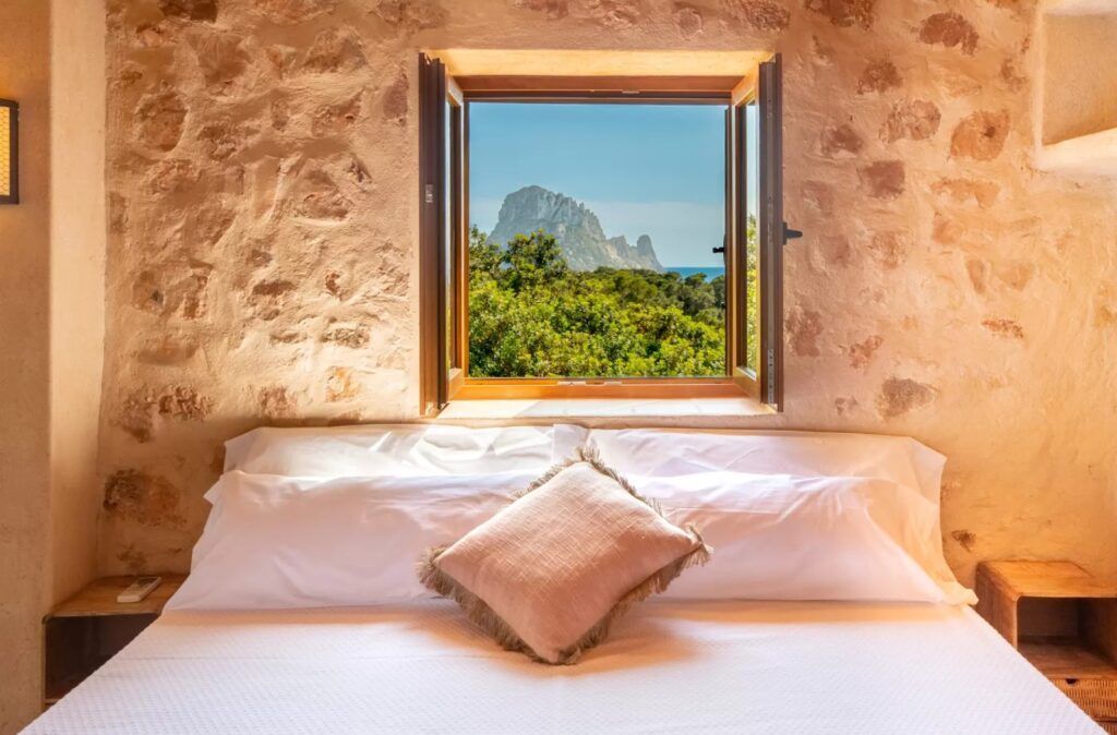 Cama con ventana abierta y vistas a Es Vedrà en Sa Païssa den Botja Ibiza